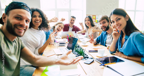 Billede på lærred We are the team! Group of happy and excited young multi ethnic businesspeople making selfie and gesturing