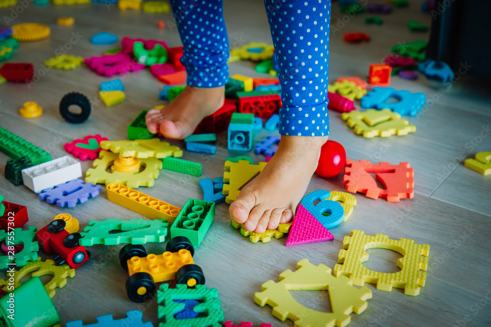 too much toys at home- girl steps on toys trying to go through