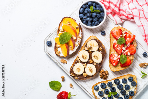 Sweet toast assortment with fresh fruit and berries on white.