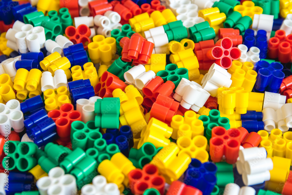 Multicolored plastic building blocks of the designer. Background of plastic colored details building blocks. Parts of bright small spare parts for toys. Close up. Multicolored plastic building blocks of the designer. Background of plastic colored details building blocks. Parts of bright small spare parts for toys. Close up.