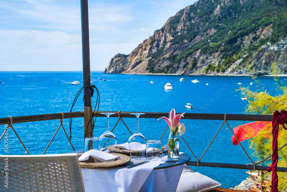 Elegantly served table with sea view / mountain view of the sea / wine glasses and a flower in a vase / restaurant in Monterosso
