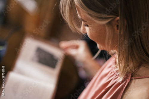 Fotografija Closeup warm portrait of a beautiful pensive romantic blonde girl reading a book in a cafe