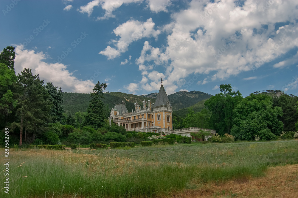 Old manor, castle among forest trees and near Crimean mountains in the beginning of summer