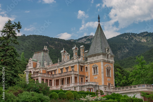 Old manor  castle among forest trees and near Crimean mountains in the beginning of summer