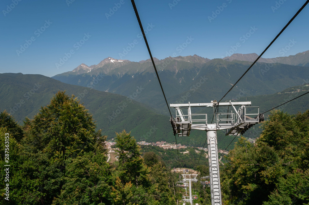 cableway on a sunny summer day in the mountains among the green forest of the Caucasus mountains