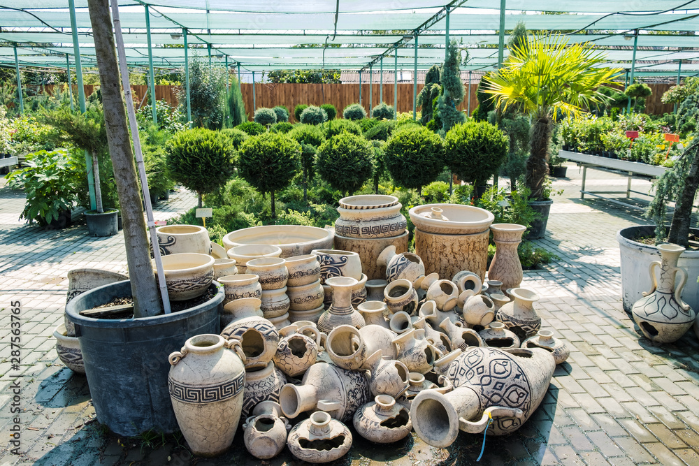 Many clay pots lie on the ground against the background of green trees.