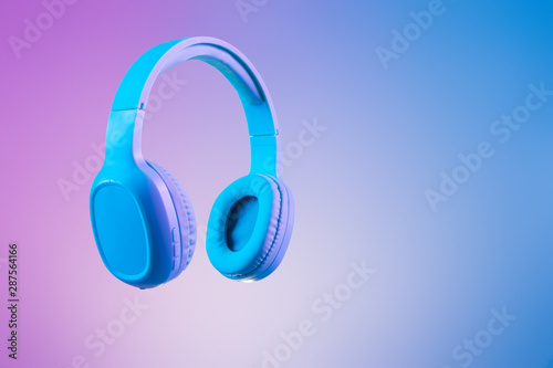 Stylish blue headphones on multi coloured / duo tone background lighting