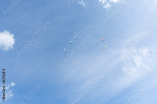 Circle of Paragliders in a sky with one outside