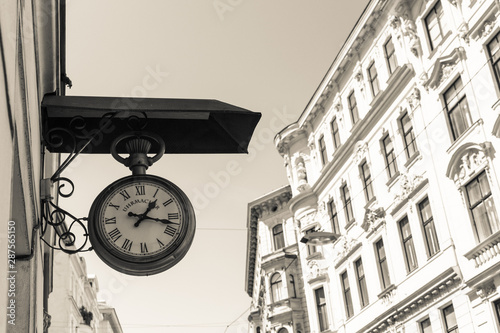 Nice photo of old clock with a building in the background in black and white colour