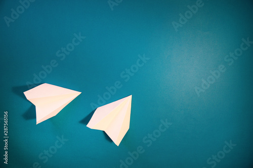 White, small, paper plane on a blue background.