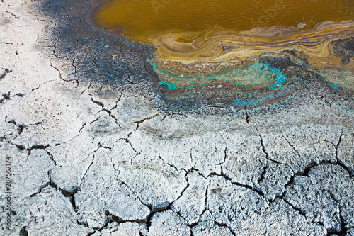 Heat, drought, climate disaster. Saline soil, dry riverbed, cracked earth, the remains of water in a dirty puddle. Close-up, background, Wallpaper, design. Selective focus.
