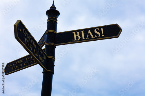 Handwriting text writing Bias. Conceptual photo inclination or prejudice for or against one demonstrating group Road sign on the crossroads with blue cloudy sky in the background