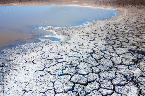 Heat, drought, disaster, saline soil, dry riverbed, blue sky reflected in the remnants of water. Bright, beautiful natural landscape. Close-up, background, Wallpaper, design. Selective focus. photo