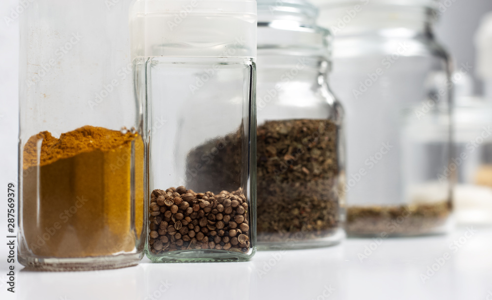 Different seasoning in glass cups, on white background. 