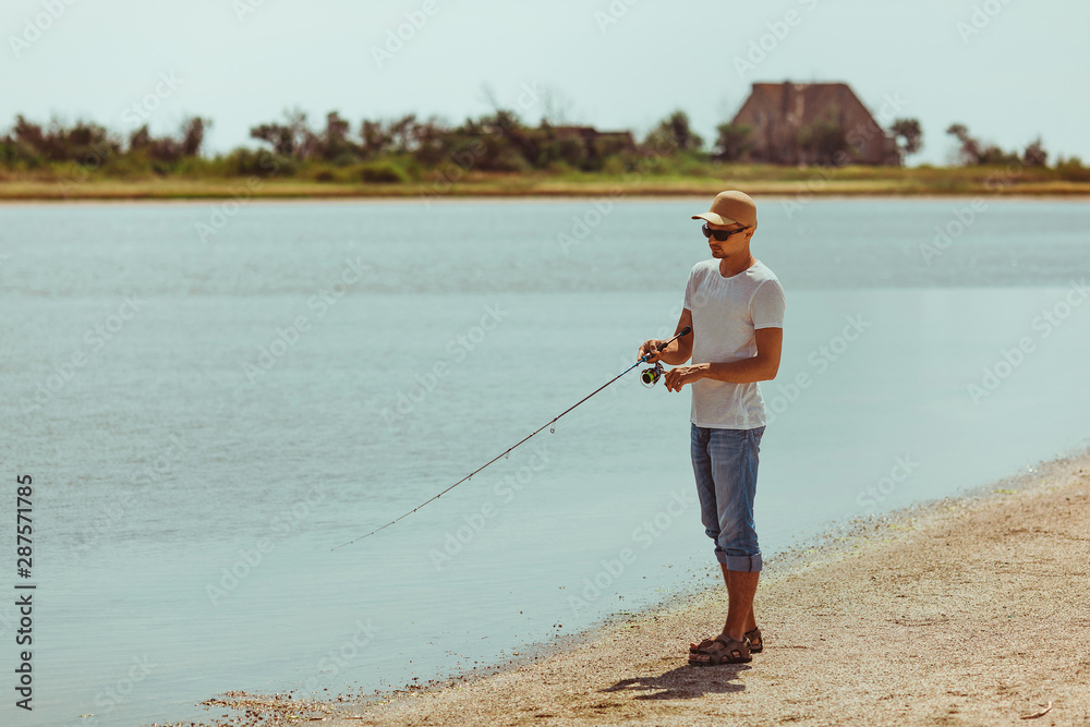 Young man fishing at sea from the shore. fisherman uses spinning Young man fishing at sea from the shore. fisherman uses spinning