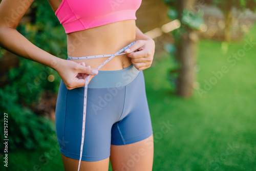 Fitness Woman With Tape Measure Showing Her Waist