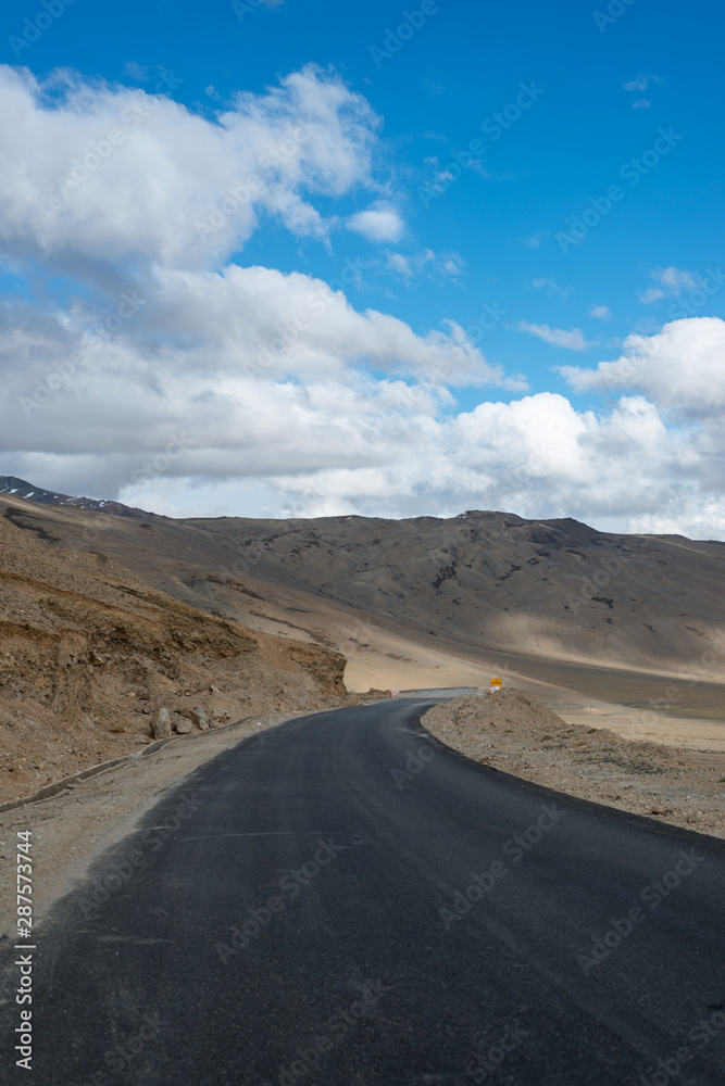 Road in mountains Himalayas and dramatic clouds on blue sky. Ladakh, Jammu and Kashmir, India