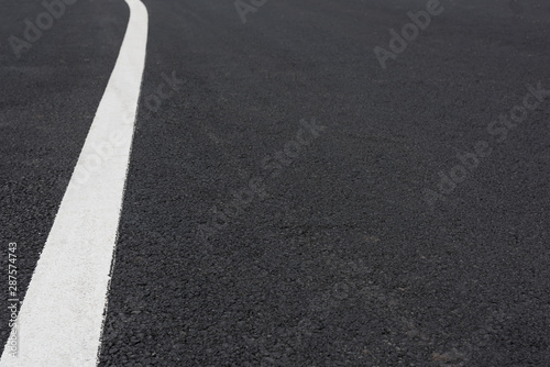 Low angle perspective view of white curved paint line on asphalt road © bqmeng