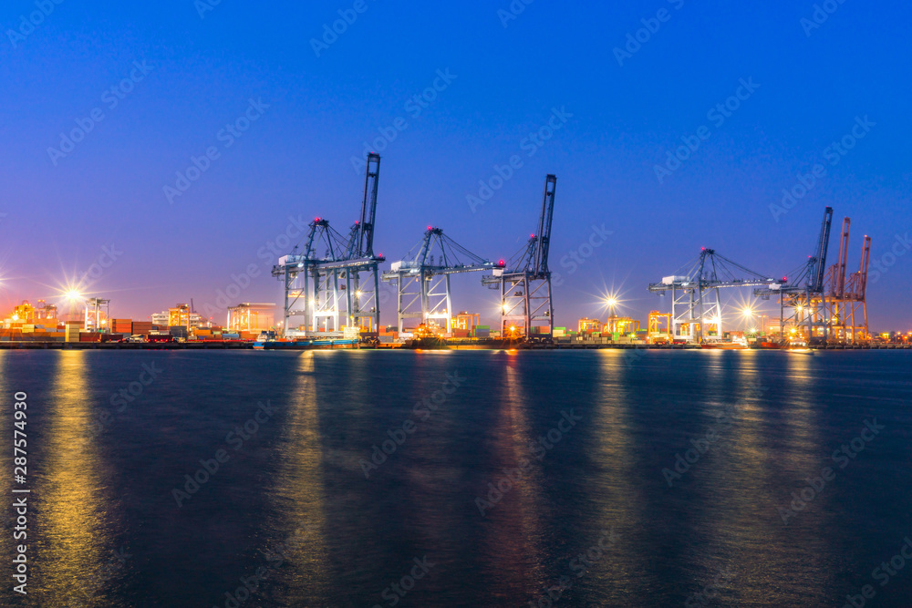 Cargo freight ship and cargo container working with crane at port area,Logistic Import Export at night, Thailand 4.0