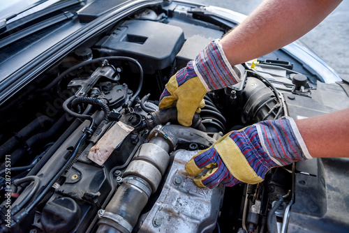 Human hands examining car engine in protective gloves close up