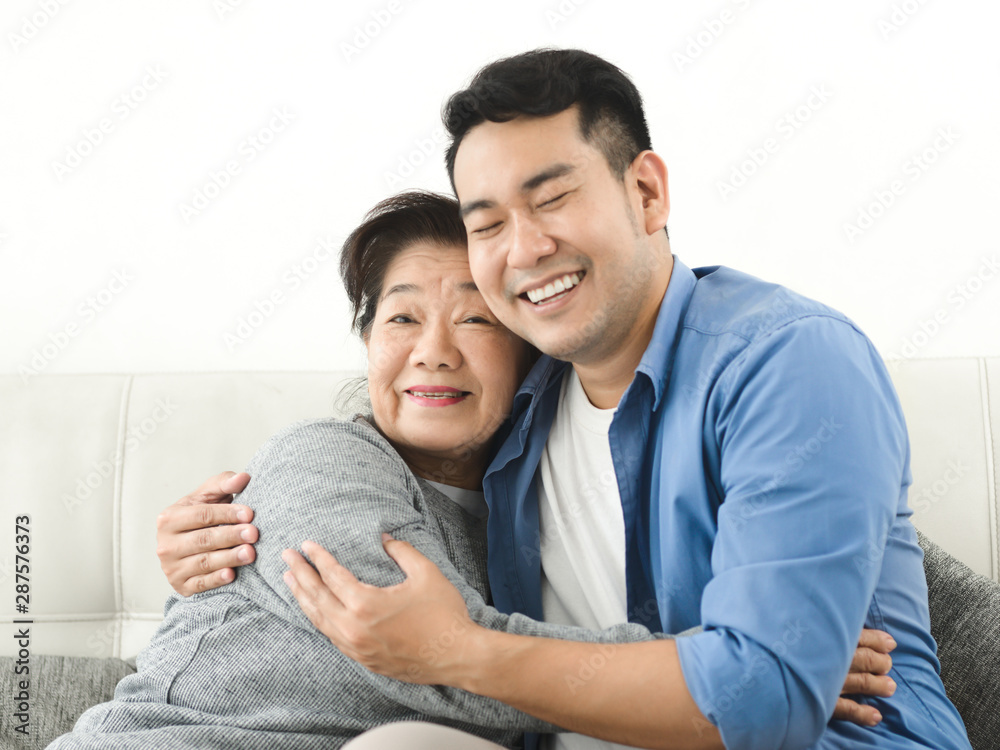 Asian mother hugging her son and sitting on sofa at home, lifestyle concept. Asian mother hugging her son and sitting on sofa at home, lifestyle concept.