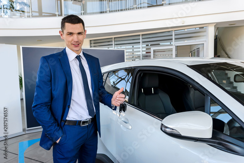 Man in showroom holding keys from new car