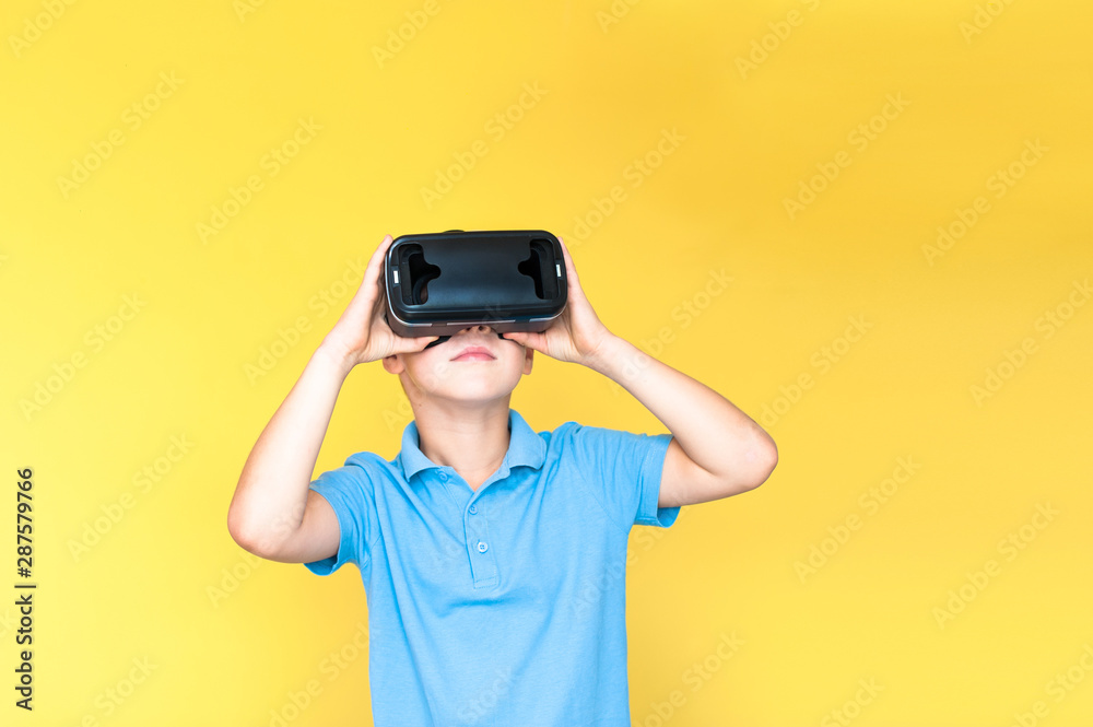 Children experiencing virtual reality isolated on yellow a background. Surprised little boy looking in VR glasses. Children experiencing virtual reality isolated on yellow a background. Surprised little boy looking in VR glasses.