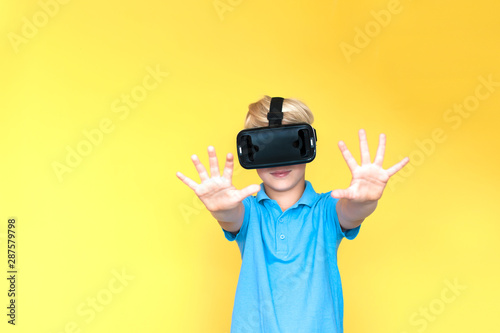 Children experiencing virtual reality isolated on yellow a background. Surprised little boy looking in VR glasses.