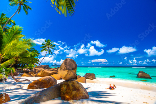 Woman sunbathing in a typical beach in Seychelles with granite rocks