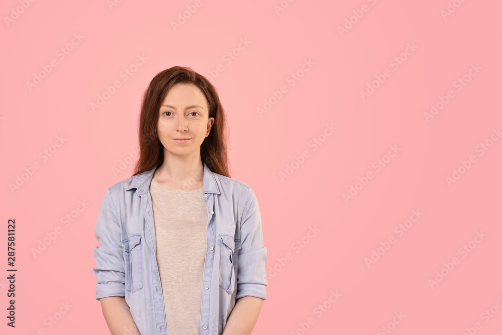 Concentrated serious young woman in casual clothes posing on a pink background advertising the services of a cleaning company. Place for text. Concentrated serious young woman in casual clothes posing on a pink background advertising the services of a cleaning company. Place for text.