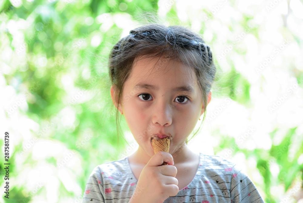 Happy child girl eating ice cream with blurred green background Happy child girl eating ice cream with blurred green background