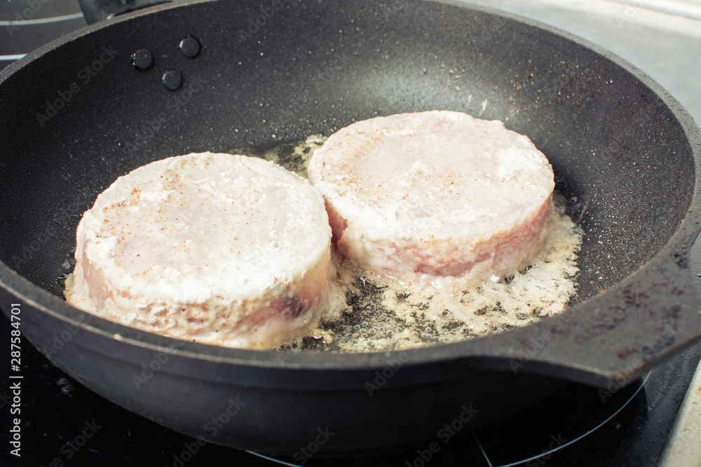 Raw pieces of fish fillet hake fried in skillet on stove. Raw pieces of fish fillet hake fried in skillet on stove.