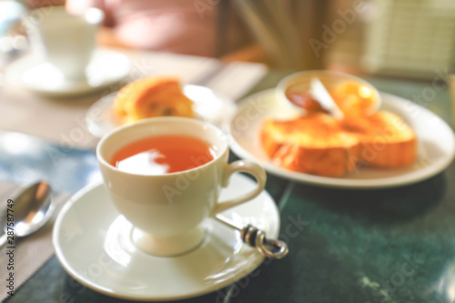Blurred image of a cup of hot tea and toasts on table
