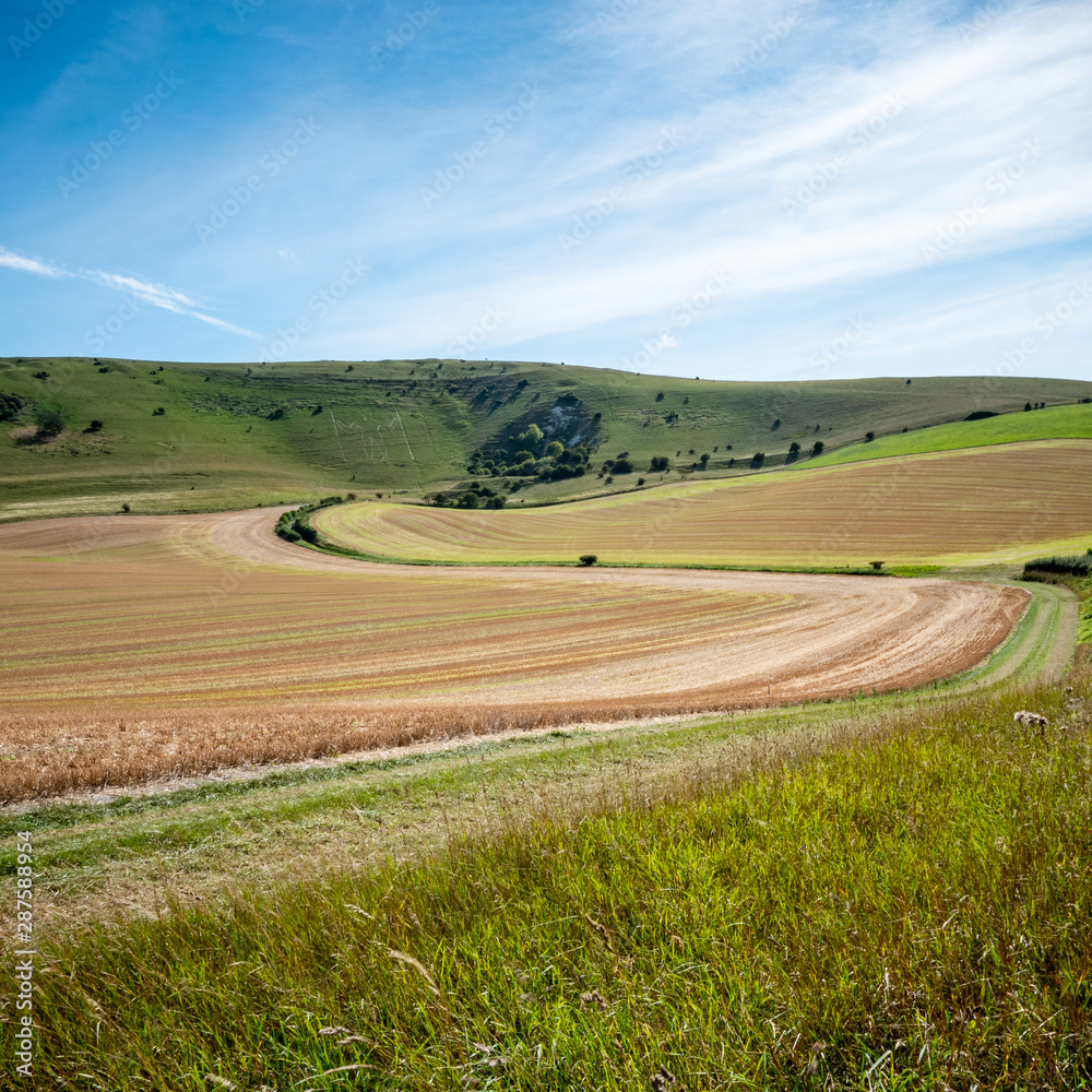 South Downs, England. A view over the rural countryside with the old landmark hill figure, The Long Man of Wilmington visible on the distant slopes.
