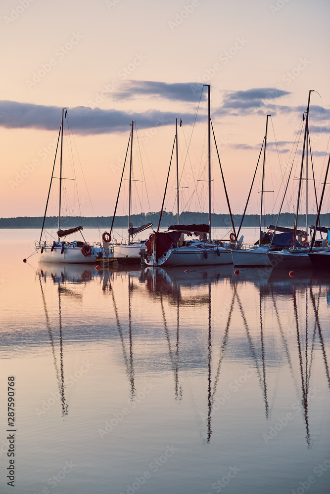 Yachts and boats moored in a harbour at sunrise. Candid people, real moments, authentic situations