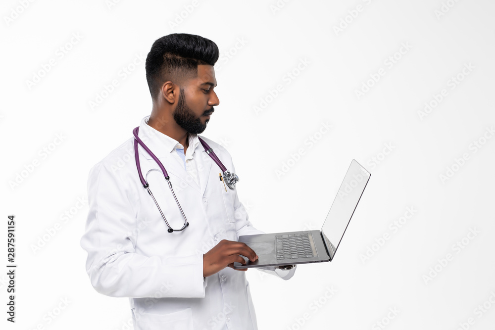 Young middle east doctor standing with Stethoscope and laptop. Smiling indian doctor with white cloth standing and thumb up. Young Doctor man with Beard and happy face. Healthcare concept. Young middle east doctor standing with Stethoscope and laptop. Smiling indian doctor with white cloth standing and thumb up. Young Doctor man with Beard and happy face. Healthcare concept.