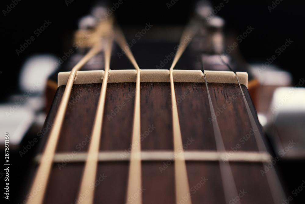 Nut and strings of acoustic guitar on a black background. Nut and strings of acoustic guitar on a black background.
