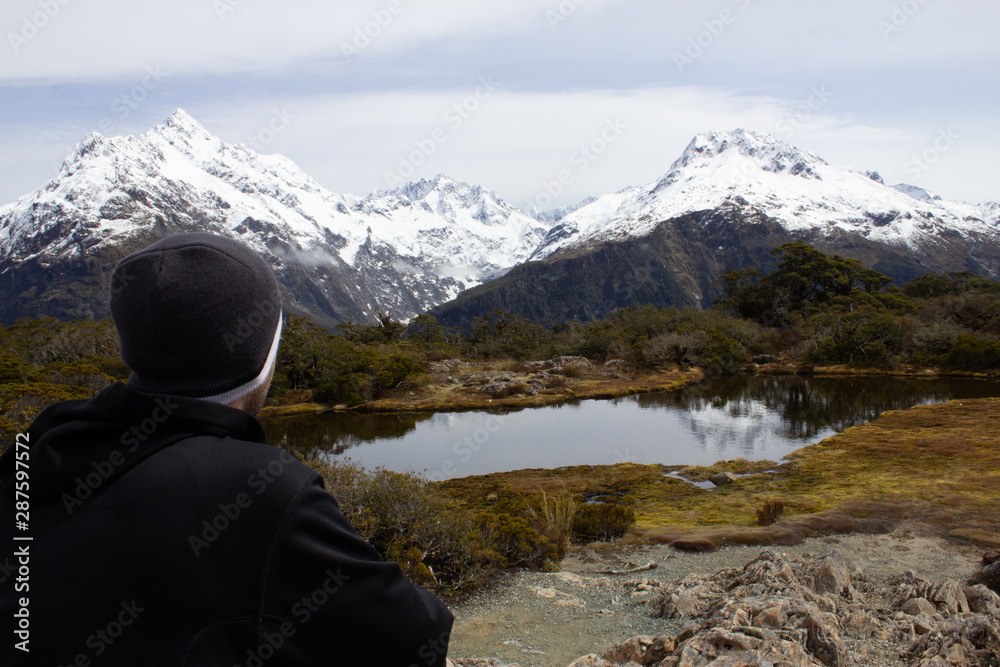 Fototapeta premium Milford Sound Summit Trek Man looking at a beautiful view of mountains at summit
