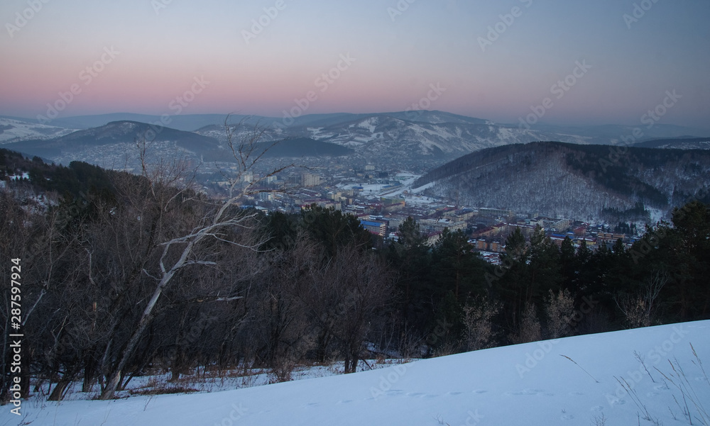 Night mountain on the background of the town village under a sunset sky