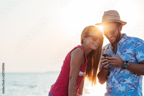 Young happy couple using smartphone by the sea