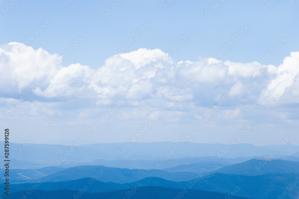 landscape with blue silhouettes of hills and mountains with blue sky. Background