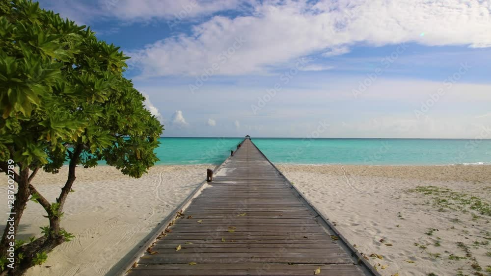 Long wooden pier leading from tropical forest in inland to private water villas and jetty with a boat. Long wooden pier leading to water villas on the Maldives On the Maldives. Long wooden pier leading from tropical forest in inland to private water villas and jetty with a boat. Long wooden pier leading to water villas on the Maldives On the Maldives.