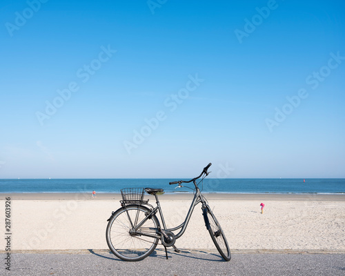 lonely bicycle near large sandy beach of german island norderney off the coast of ostfriesland under blue august sky in summer