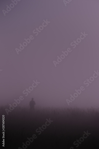 The silhouette of a man in the night fog lit by moonlight