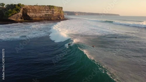 Aerial view of a surfer riding a wave at Bali during sunset
