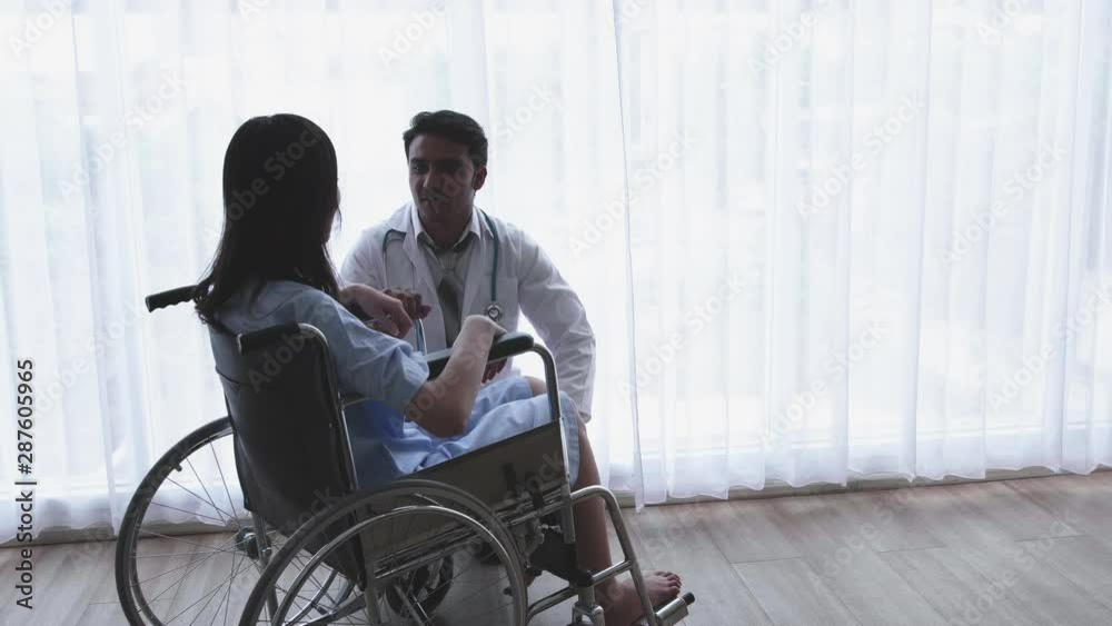 Doctor is encouragement and empathy asian women patient's, disabled leg sitting in a wheelchair in a home or hospital That has sunlight from the window. Doctor is encouragement and empathy asian women patient's, disabled leg sitting in a wheelchair in a home or hospital That has sunlight from the window.