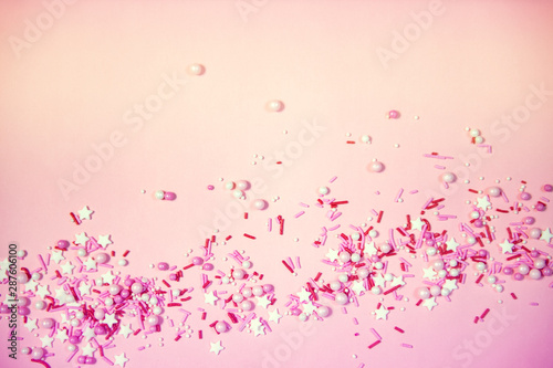 Colorful sprinkles on a pink background  top view with copy space