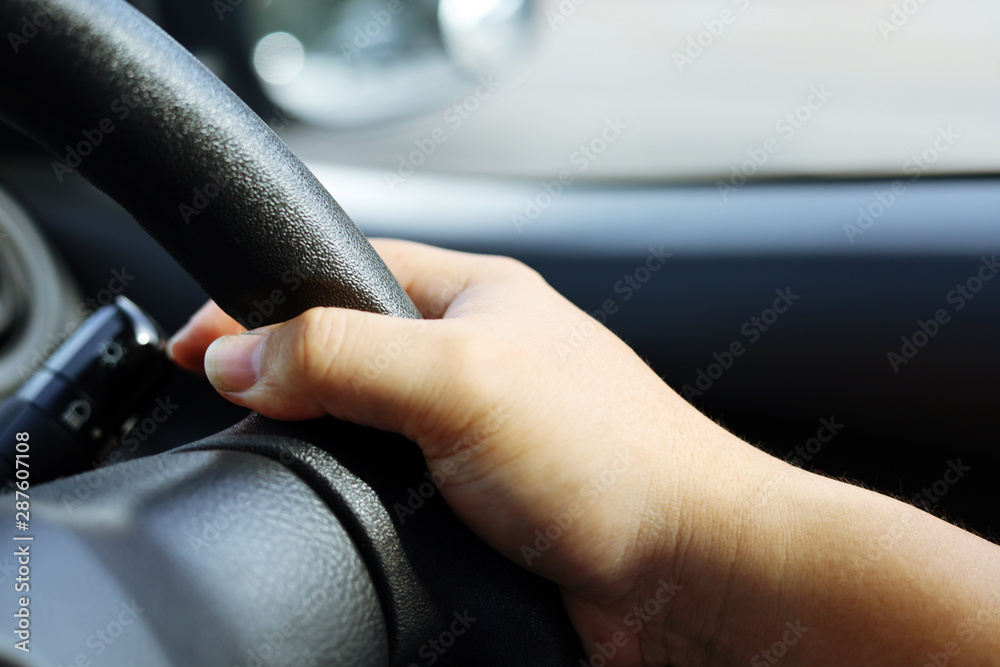 Close-up Hand holding the steering wheel of the car while driving.
