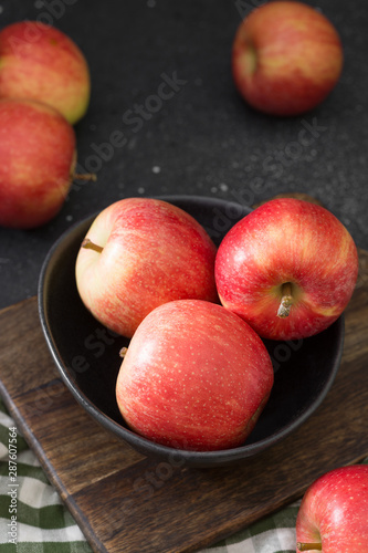 Apples in a black bowl on a wooden Board. Dark background