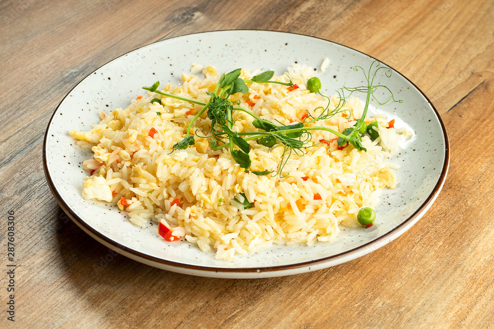 Rice with vegetables and omelet in whte plate on wooden background. Healthy and balanced food for athletes and diet. Food photo background Rice with vegetables and omelet in whte plate on wooden background. Healthy and balanced food for athletes and diet. Food photo background